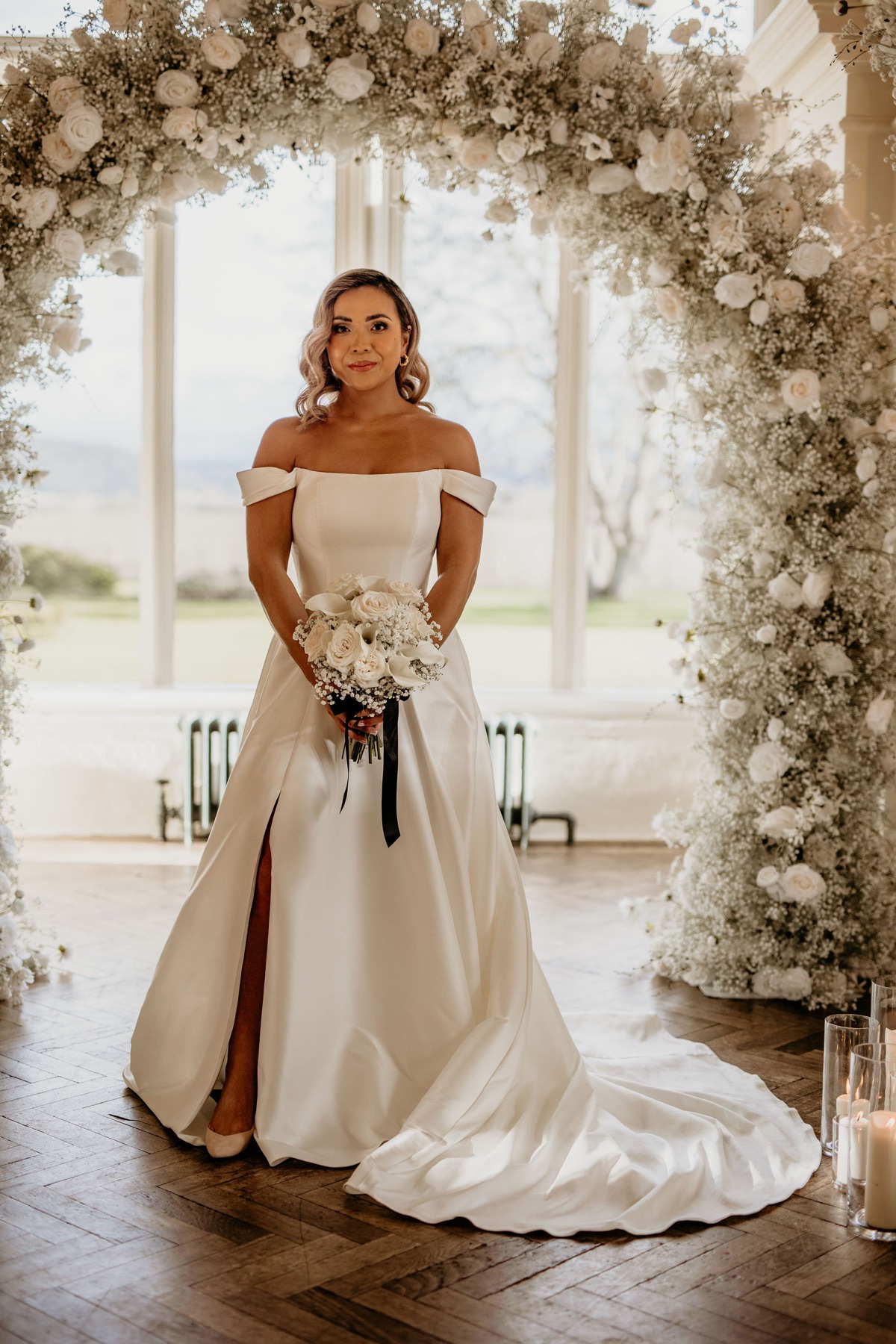 A bride beneath the floral arch at Glewstone Court